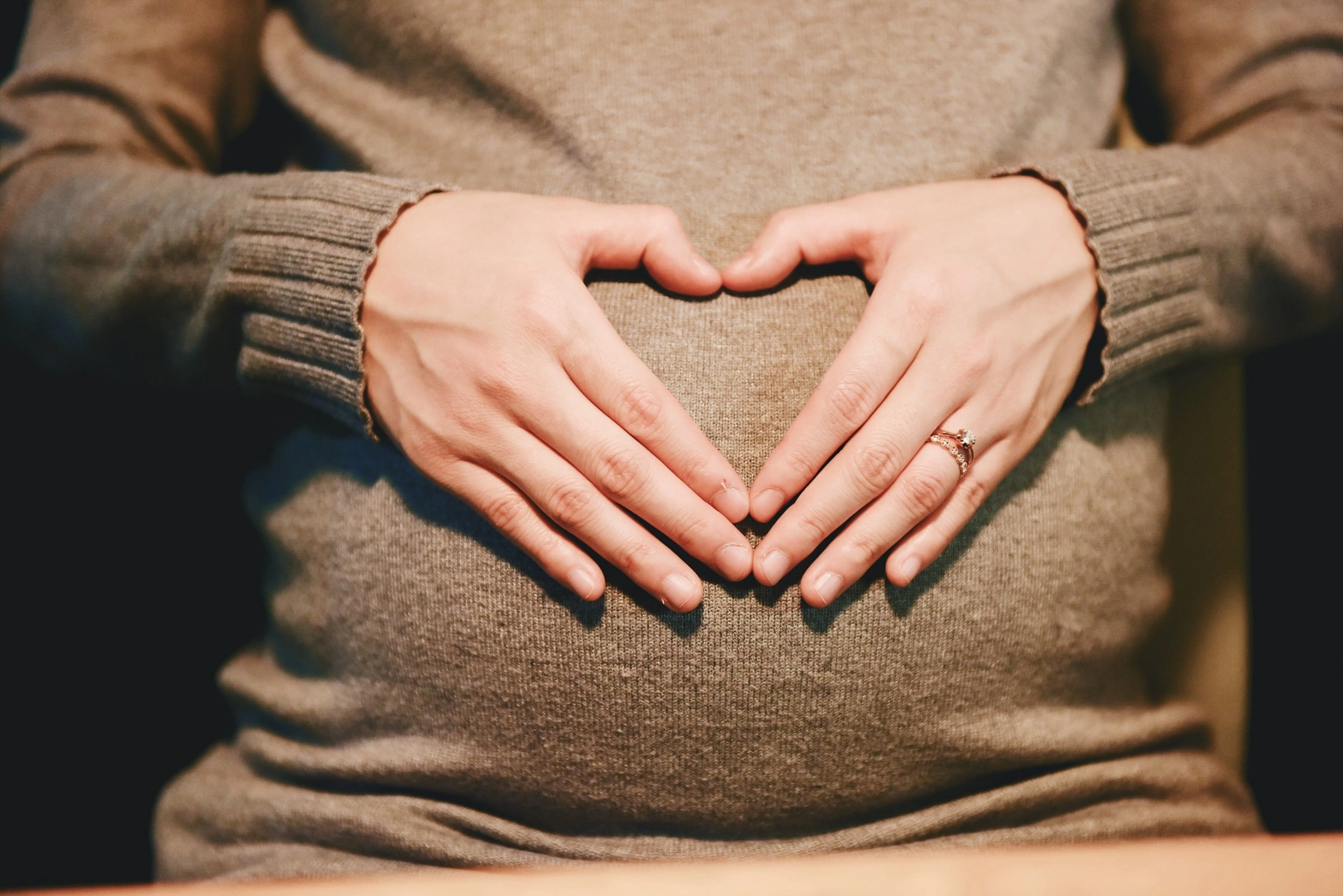 Four Arms Show Heart on Stomach of Pregnant Woman Stock Photo