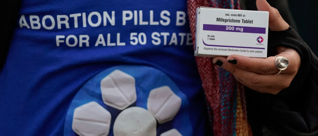 A person's hand holds a box of mifepristone