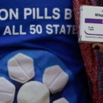 A person's hand holds a box of mifepristone