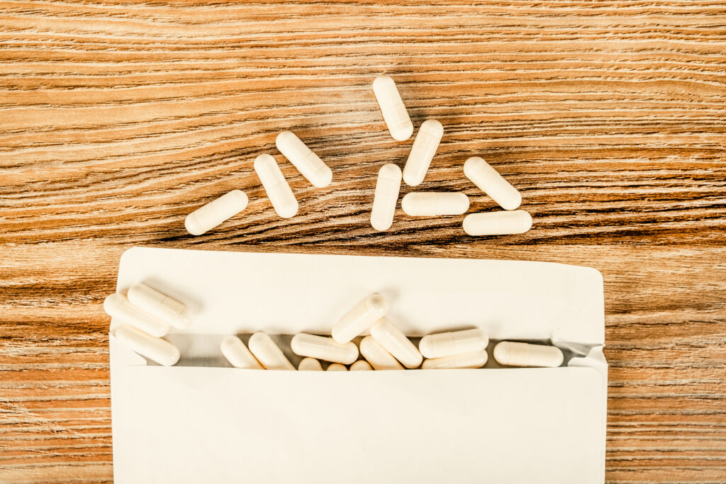 White capsules spilling from an open white paper package onto a wooden surface, with several capsules scattered above the package—an image evoking the ongoing debate over America’s abortion law.