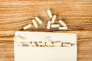 White capsules spilling from an open white paper package onto a wooden surface, with several capsules scattered above the package—an image evoking the ongoing debate over America’s abortion law.