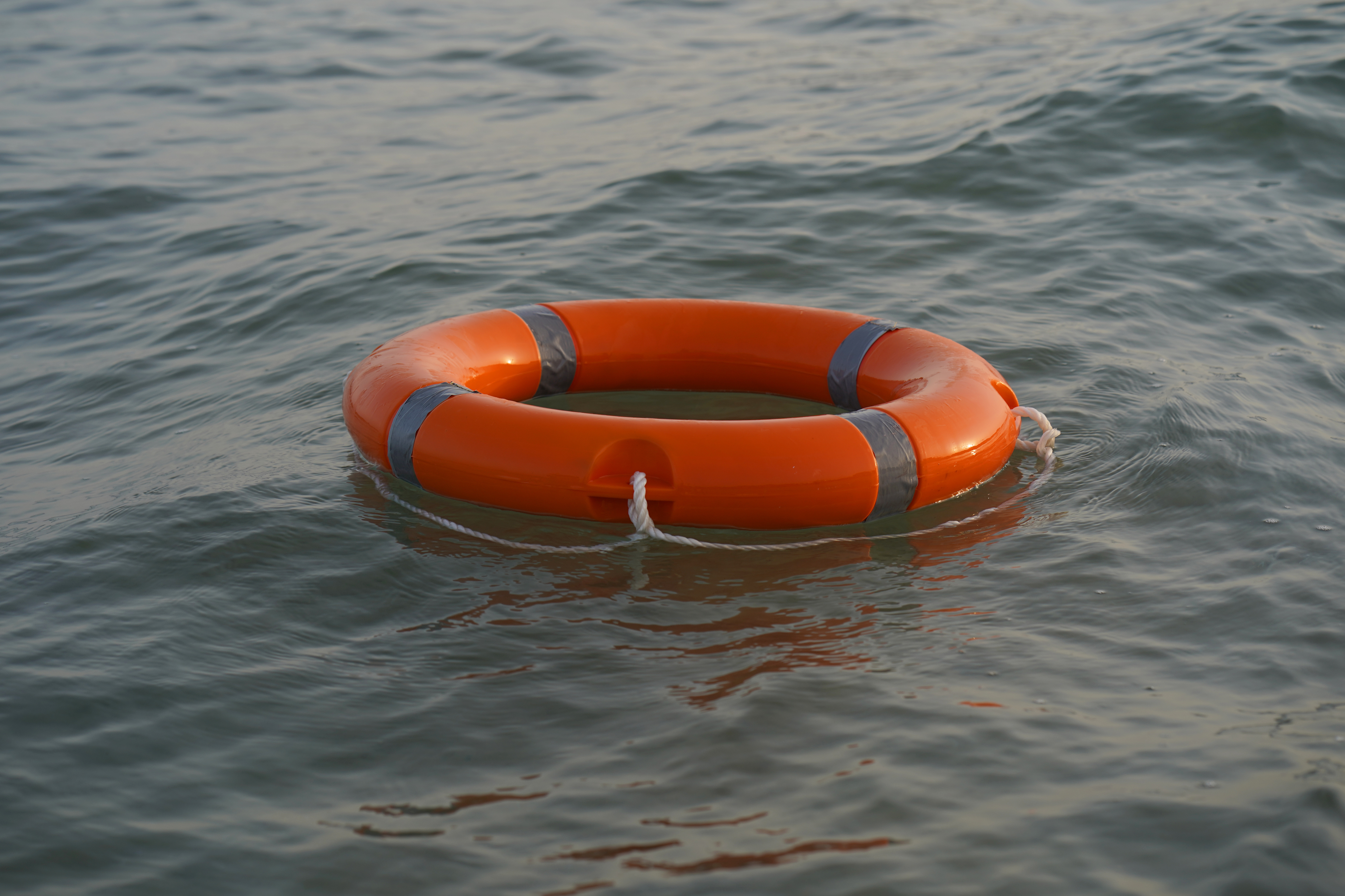 An orange life ring with silver reflective stripes floats on the surface of calm water, much like how ongoing discussions about the Hyde Amendment impact continue to ripple through society.