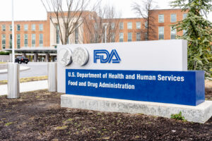 A sign for the FDA featuring the agency’s logo and circular seals in front of a brick government building, where clinical guidance for mifepristone REMS is often determined.